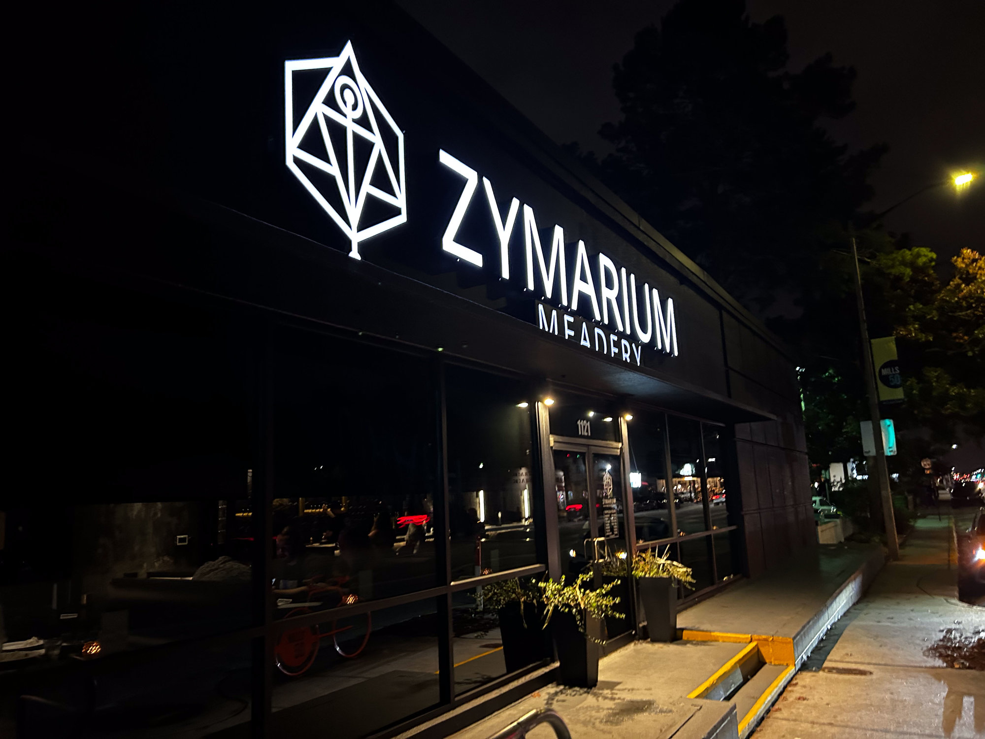 outside of zymarium meadery at night with white lit up sign